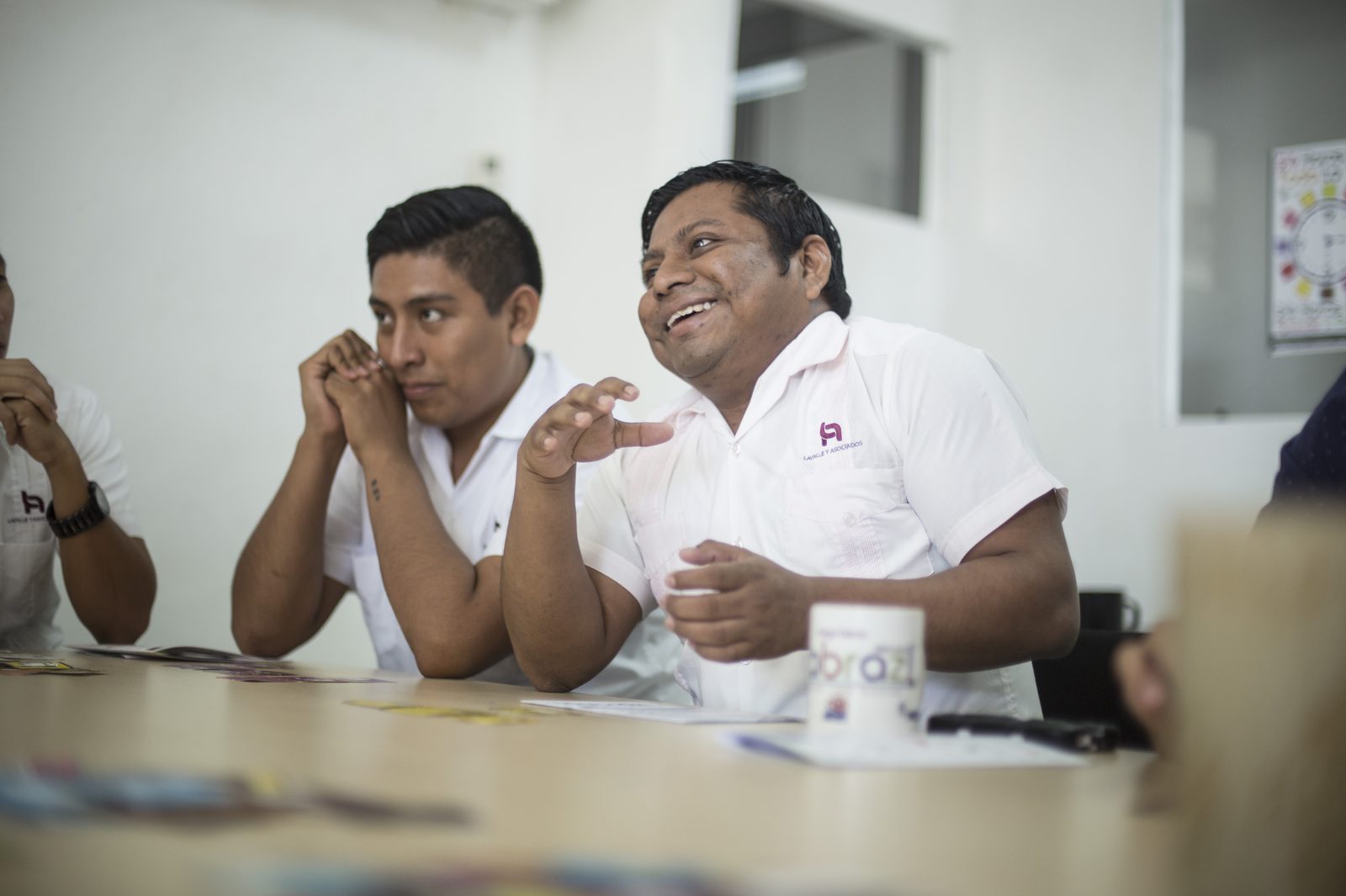 Colaboradores de Lavalle y Asociados conversando animadamente con taza Habraz sobre la mesa