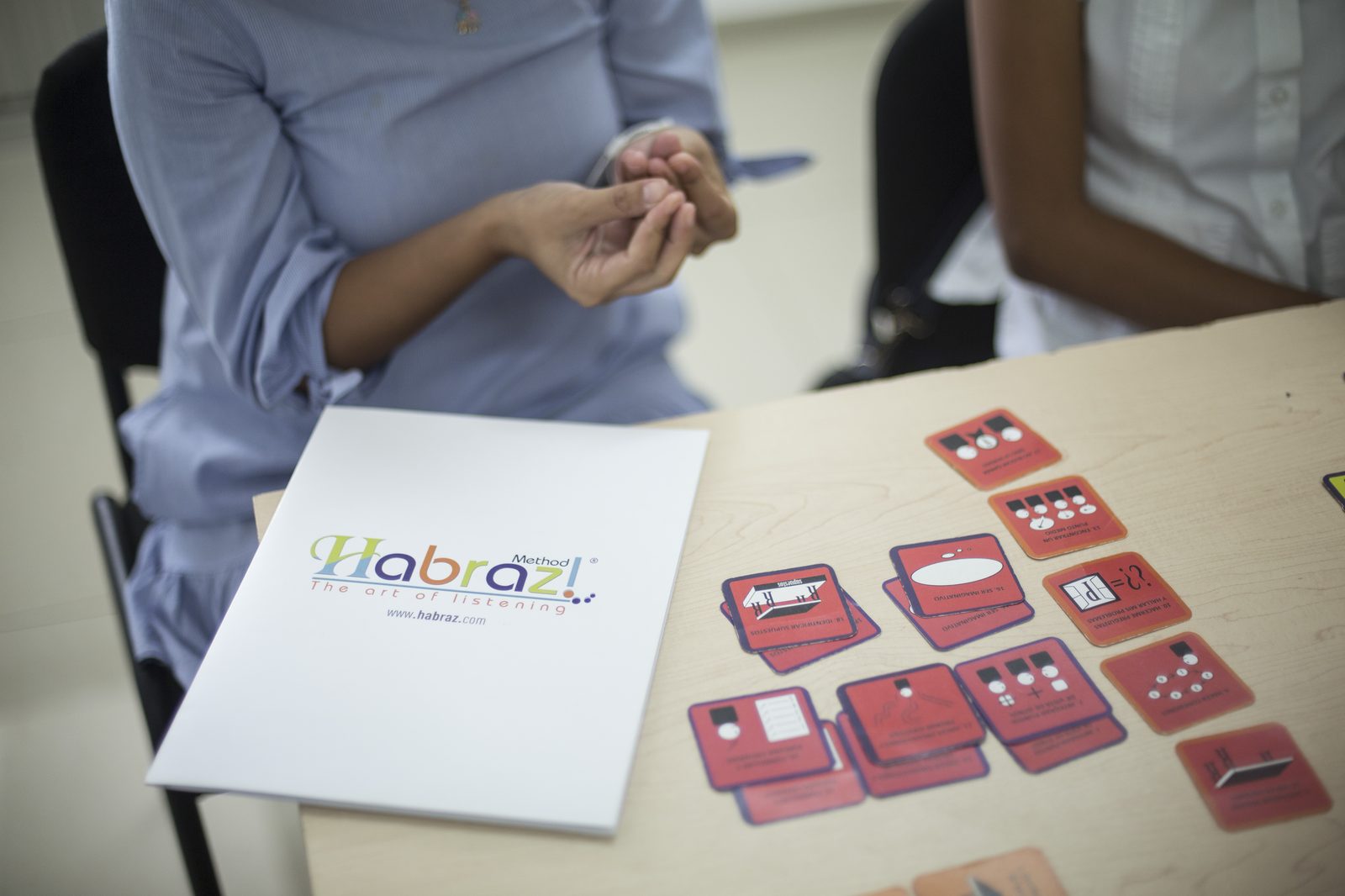 Carpeta del Método Habraz junto a tarjetas rojas de la dinámica sobre la mesa de trabajo