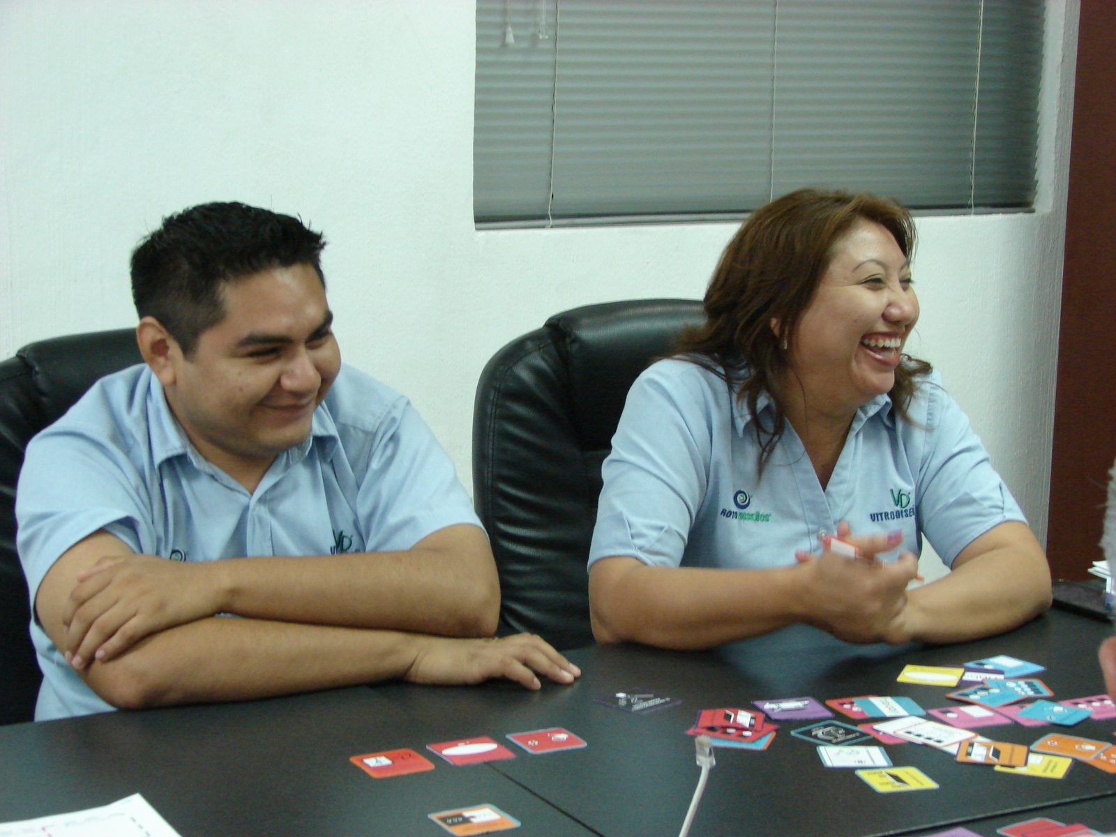 Colaboradores Vitrofibras VFS riendo con tarjetas Habraz sobre la mesa